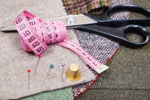 pink measure tape, pins, thimble, shears on cloth
